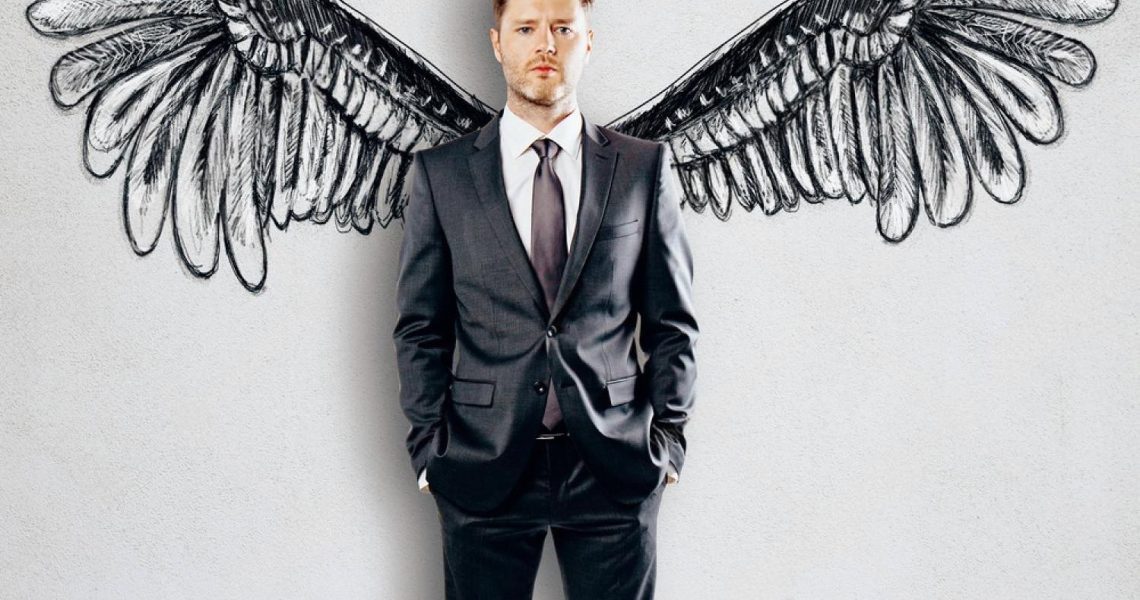 Man in a suit standing in front of sketched wings, symbolising financial independence and freedom