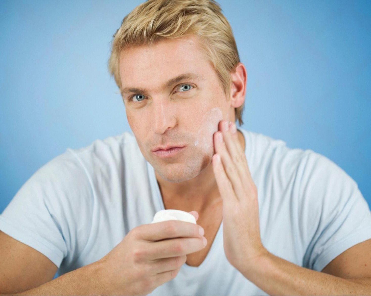 Man applying post-shave balm to his cheek to prevent razor burn and ingrown hairs